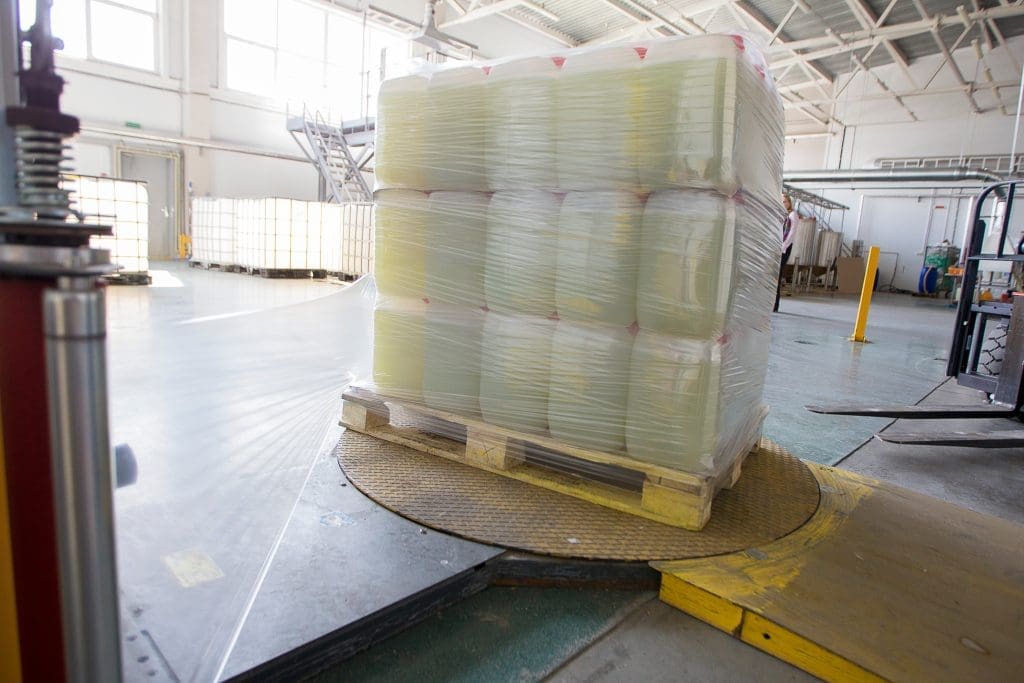 A pallet of liquid containers being wrapped by a palletizing machine