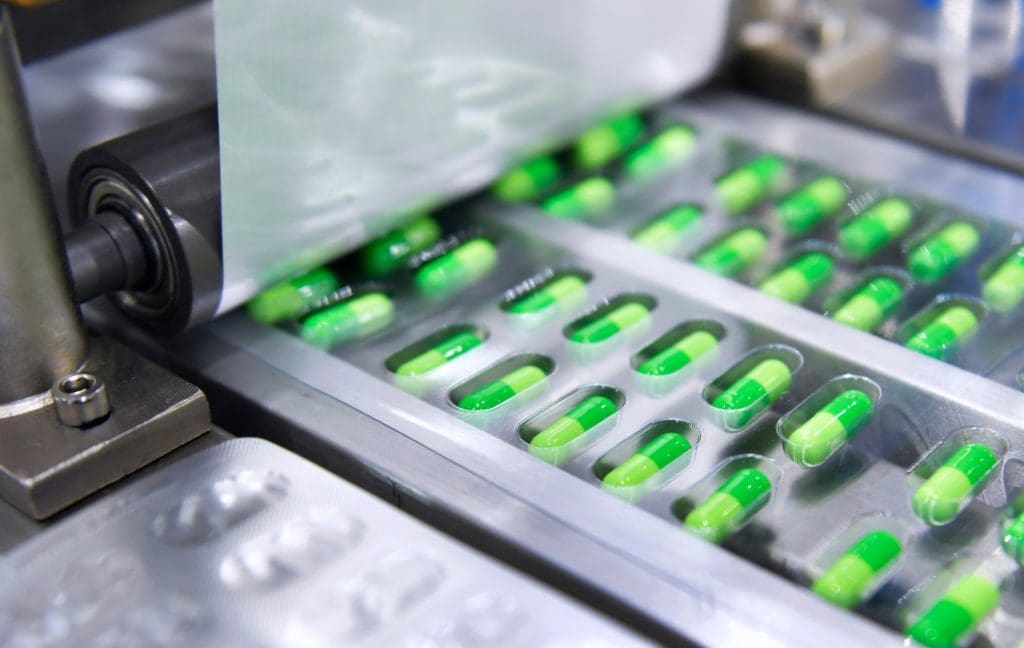 A package of green capsules in the process of being sealed