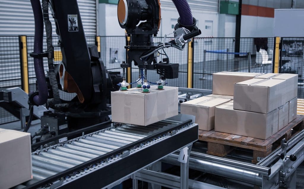 A packaging automation system moving brown boxes onto a conveyor belt