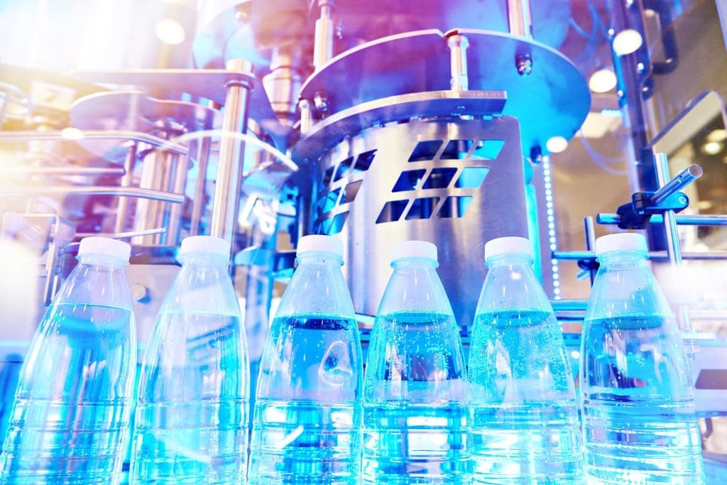 Bottles filled with a clear liquid on a conveyor belt.