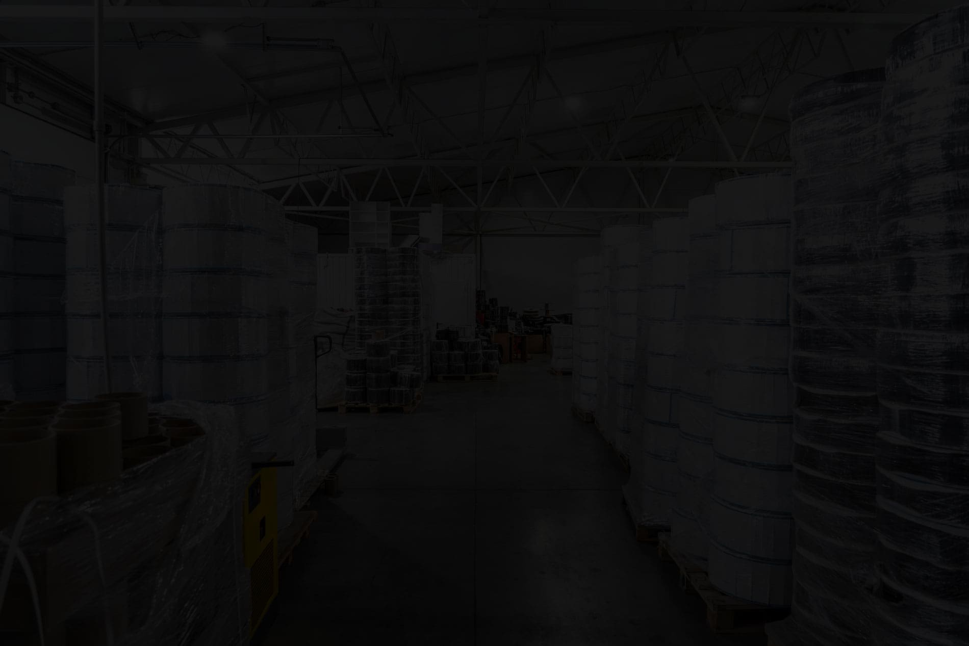 Industrial warehouse with large rolls of packaging film and plastic wrap stacked on pallets