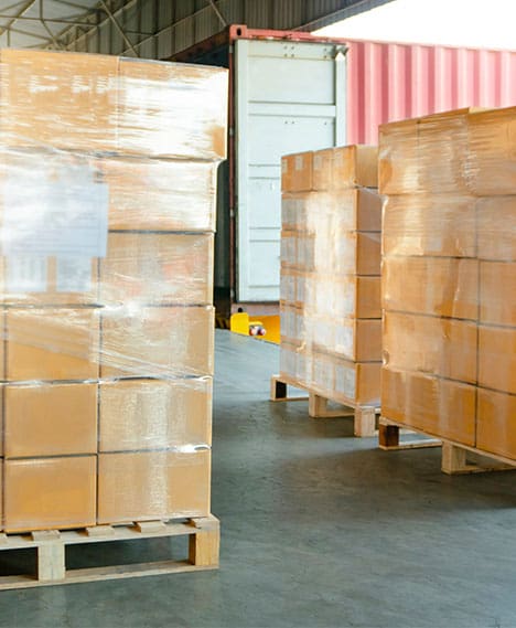 A stack of plastic wrapped boxes in a warehouse.
